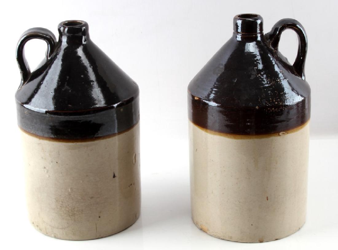 SET 2 ANTIQUE RCP STONEWARE POTTERY MOONSHINE JUGS: Set of two (2) vintage two-tone brown and tan stoneware pottery moonshine jugs with large hoop handles. Inscribed on bottom with "RCP CO. Akron O", the trademark for Robinson Clay Products (1902-1975)