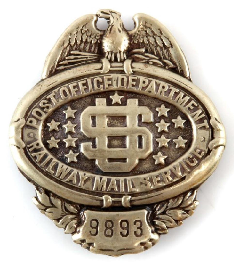 OBSOLETE POST OFFICE RAILWAY MAIL SERVICE BADGE: Marked "9893" on front; "C.G.B RAXMAR IO MAIDEN LANE NEW YORK" on reverse. In excellent condition. Measures approximately 2 1/4" long by 2" wide.