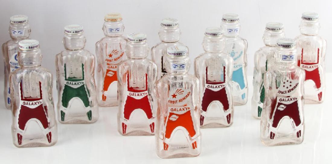 LOT OF 12 GALAXY SPACE BOMBARDIER SYRUP BOTTLES: Double as coin banks. One orange syrup and the rest black raspberry. From the 1950s. In excellent condition with no chips or cracks. Please acquire third party shipping estimate prior to bidding.