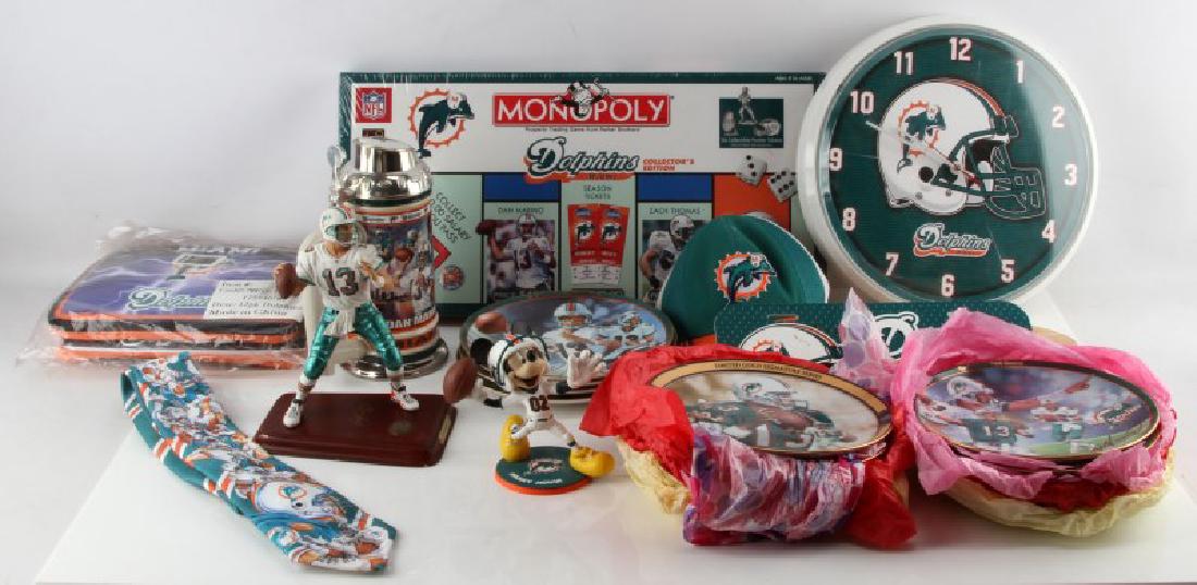MIXED LOT OF MIAMI DOLPHINS COLLECTIBLES: Mixed lot of Miami Dolphins collectibles. Includes unopened Dolphins cooler, hat, unopened Monopoly board game, clock, plaque, Dan Marino figurine, tie, 14 collectable plates, Mickey Mouse player figu