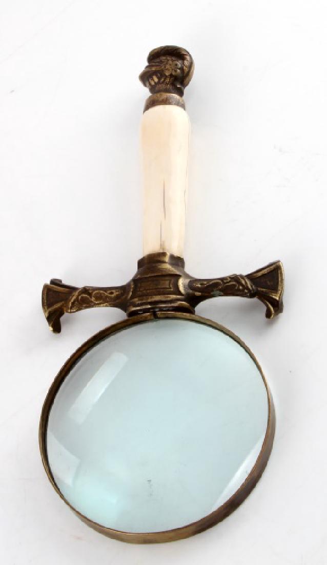 ANTIQUE MAGNIFYING GLASS WITH TUSK HANDLE: With bronze knight's head pommel. Measures 10" long, and magnifying glass has a diameter of 4". Weighs 422 grams overall. In very good condition with cracks in handle.