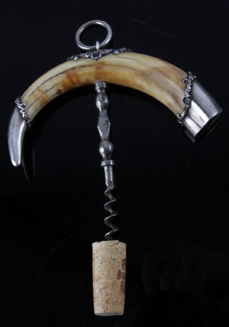 ANTIQUE SILVER CAP WARTHOG TUSK CORKSCREW: Marked, "STERLING" at the top. The end, monogrammed, "MEL". The corkscrew measures 5" from bottom of screw to handle. The tusk handle measures 8 1/2", measured on a curve. These pieces are over 100 ye