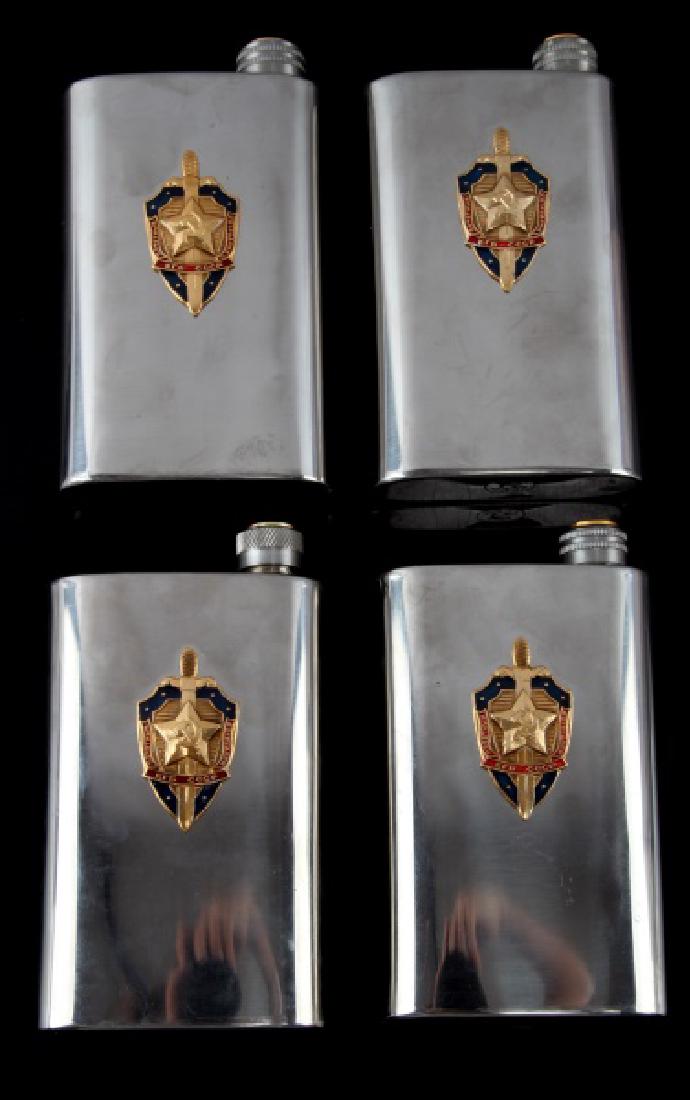 RUSSIAN USSR CCCP KGB DRINKING FLASK LOT OF 4: 4 identical stainless steel KGB drinking flasks. Each flask has the emblem of the KGB emblazened on the front, and a Hammer and Sickle "CCCP" stamp on the bottom. The caps have a profile image of Vlad