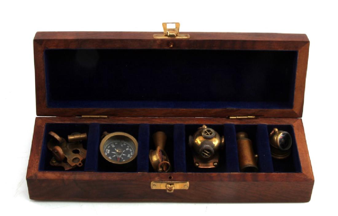 SMALL WOODEN BOX W NAUTICAL THEMED BRASS PIECES: Measures 9 1/2" by 3" and is 1 1/2" deep with 6 compartments. Includes 6 small pieces ranging from a compass to a old divers helmet.