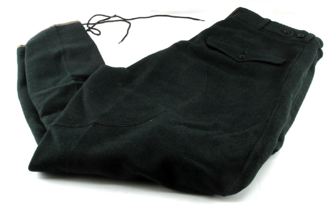 WWII GERMAN THIRD REICH UNIFORM BREECHES: Dark green uniform breeches in the distinctive style of the Third Reich, with the deeply flared cut above the knee tapering down to fit inside high boots over the calfs, with lace to hold the pants in