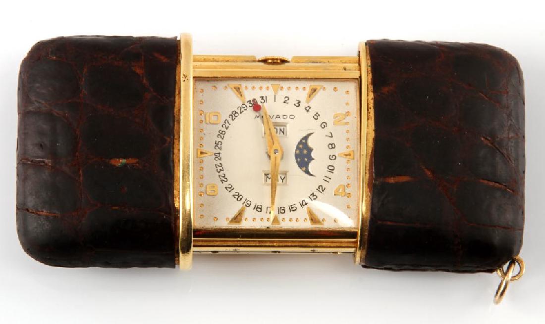 VINTAGE MOVADO TRIPLE DATE MOON PHASE PURSE WATCH: Circa 1930's, gold numbers and arrows, moon phase cut out to right side, Switzerland. Numbers 1260 and 636M marked to back. Brown snake skin exterior. Has loop for key chain. One scratch to face at to