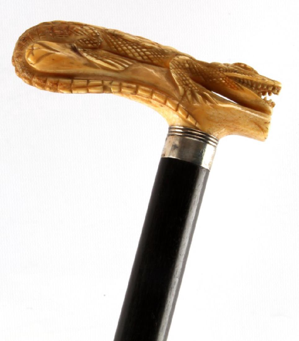 VICTORIAN WALRUS TUSK WALKING STICK W ALLIGATOR: Antique walrus tusk handle with detailed alligator carving and unmarked silver wrap measures 4 1/2 inches in lench1 7/8 inches from top of handle to base of wrap. Ebony shaft measures 33 1/5 inches in