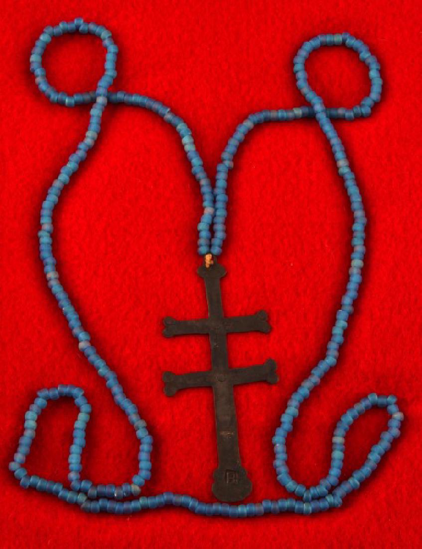 NATIVE AMERICAN ANTIQUE FUR TRADE SILVER CROSS: Silver two-barred Cross of Lorraine from the fur trade with Native Americans. It has a BH maker's mark on the bottom, 3 3/4 inches in length, with a blue Venetian bead necklace that is original to the