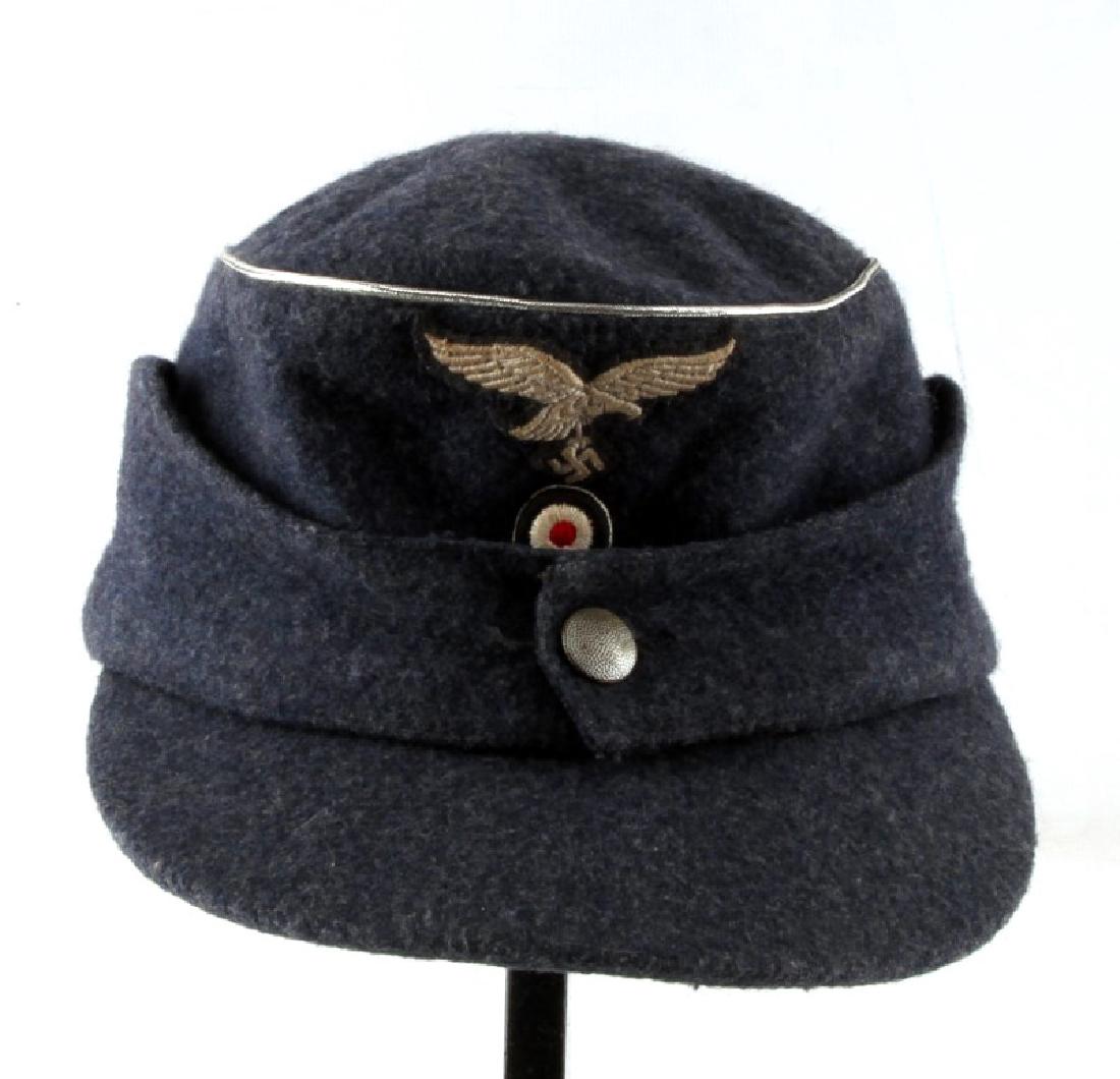 WWII GERMAN THIRD REICH LUFTWAFFE OFFICER M43 CAP: The body is a blue grey wool material with silver bullion wire piping. Has a cloth embroidered Luftwaffe Reichsadler and cockade sewn onto the front. Has a black satin lining on the inside. Medium siz