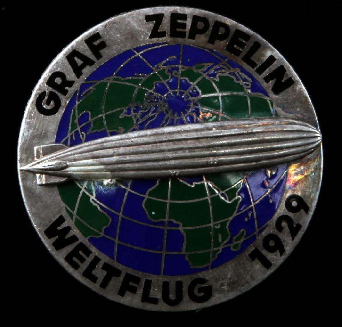 WWII GERMAN 3RD REICH GRAF ZEPPLIN AIR SHIP BADGE: Graf Zepplin Weltflug 1929 Badge. Measure 1 3/4 inches in diameter. Maker marked 'CTD' on the back. Pin back. Two piece nickel construction with enamel.