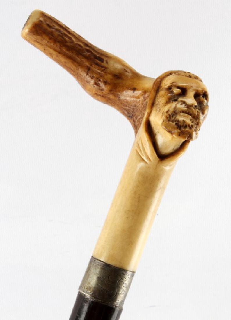 ANTIQUE BEARDED MAN CARVED HORN WALKING STICK CANE: Hand carved stag horn handle features a bearded man in a hooded tunic extending from its 90 degree turn 4 inches in width and 4 inches in length down to the sliver wrap. Wrap is monogrammed with a J o