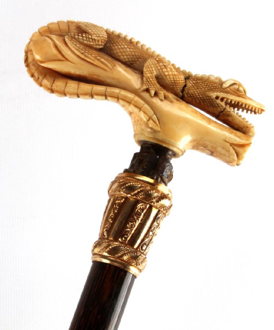 ANTIQUE WALRUS TUSK SCRIMSHAW ALLIGATOR HANDL CANE: 19th Century stick, with gold fill wrap at neck , named E.S. Gaines, handle has 2 old cracks but is intact, original ferrule tip, measures 35 by 4.25 inches. Pre 1972 we cannot ship international and