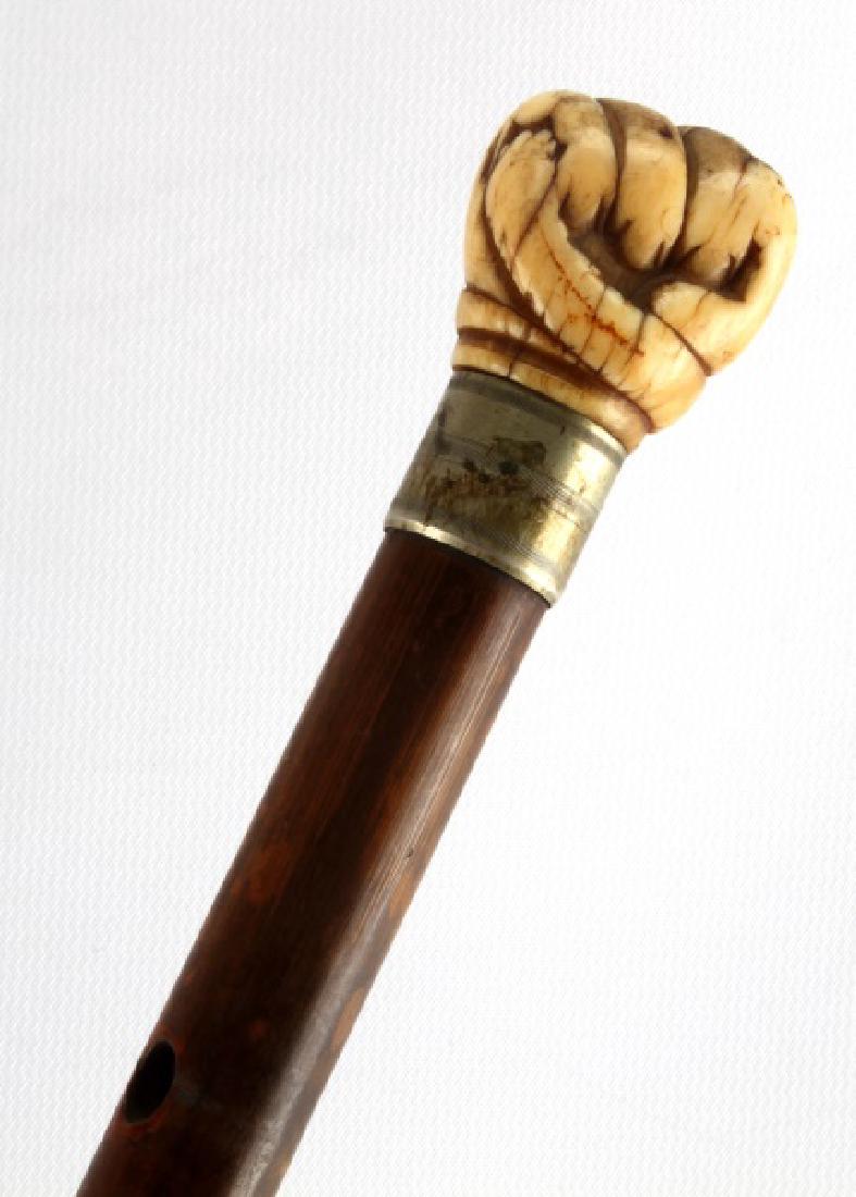 BONE FIST GRASPING SNAKE ANTIQUE WALKING STICK: Fist measure 1.33 inches, has graduated upper shaft with a lanyard hole, silver wrapped and elongated white metal ferrule tip. Overall length 34 inches. Face, Dial, Hands: john