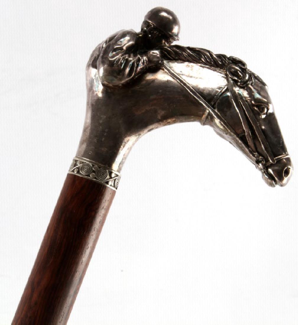 ANTIQUE SILVER HANDLE HORSE HEAD AND JOCKEY CANE: Antique cane with a horse head, with a jockey on the back of the horse, all made of silver. Polished wooden shaft, and brass ferrule, which appears original. Measures 36 inches in overall length. Head