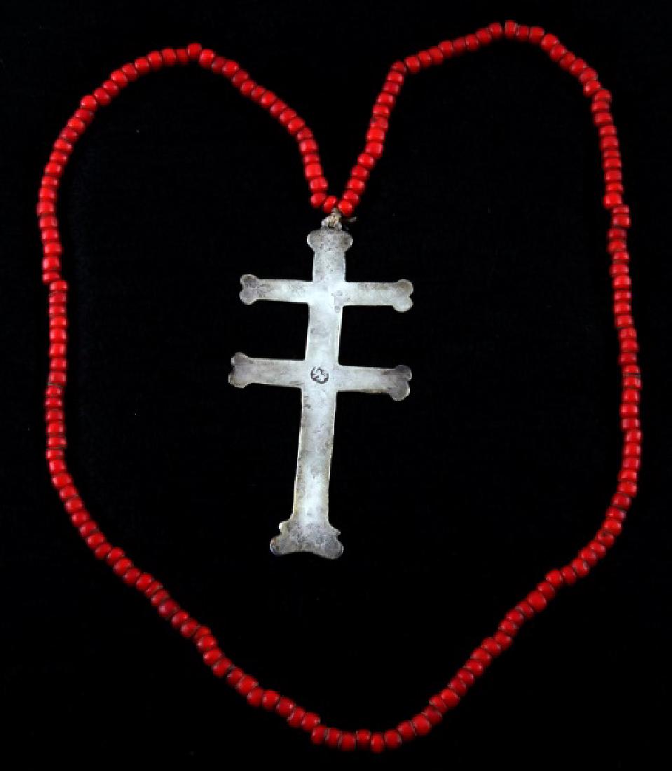 ANTIQUE NATIVE AMERICAN FUR TRADE ERA SILVER CROSS: Silver two-barred Cross of Lorraine from the fur trade with Native Americans. It bears a hallmark with a lion en passant facing left with a sword held upright, 3 1/2 inches in length, with a red bead