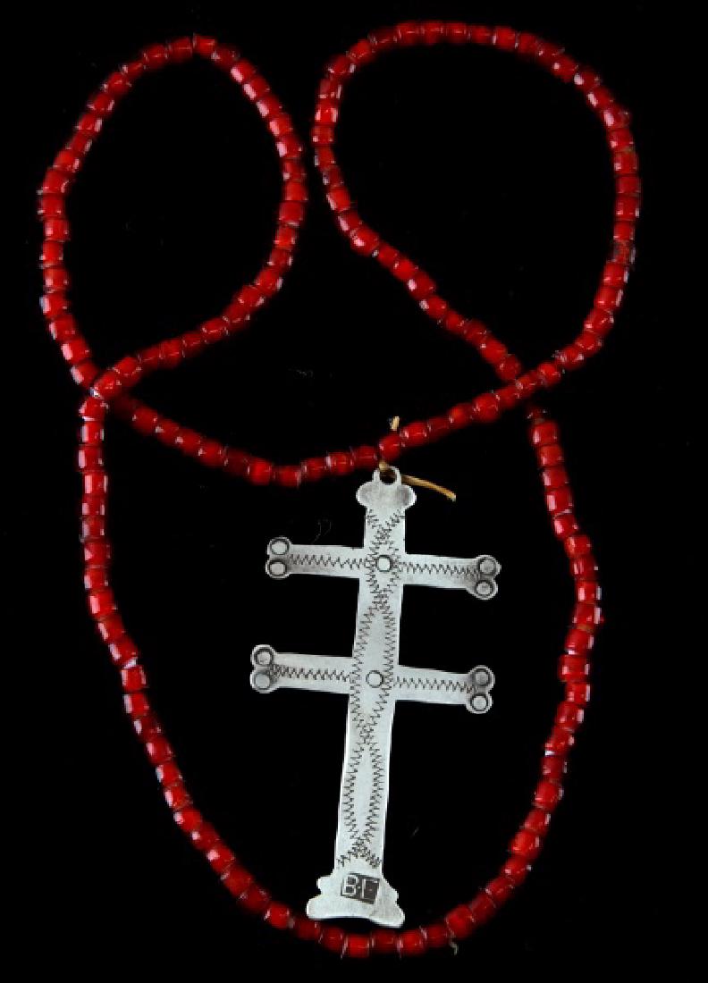 NATIVE AMERICAN ANTIQUE FUR TRADE ERA SILVER CROSS: Silver two-barred Cross, it has a BE maker's mark, 3 1/2 inches in length, with a red Venetian bead necklace that is original to the same time period, that was married to the piece at a later date. Ex