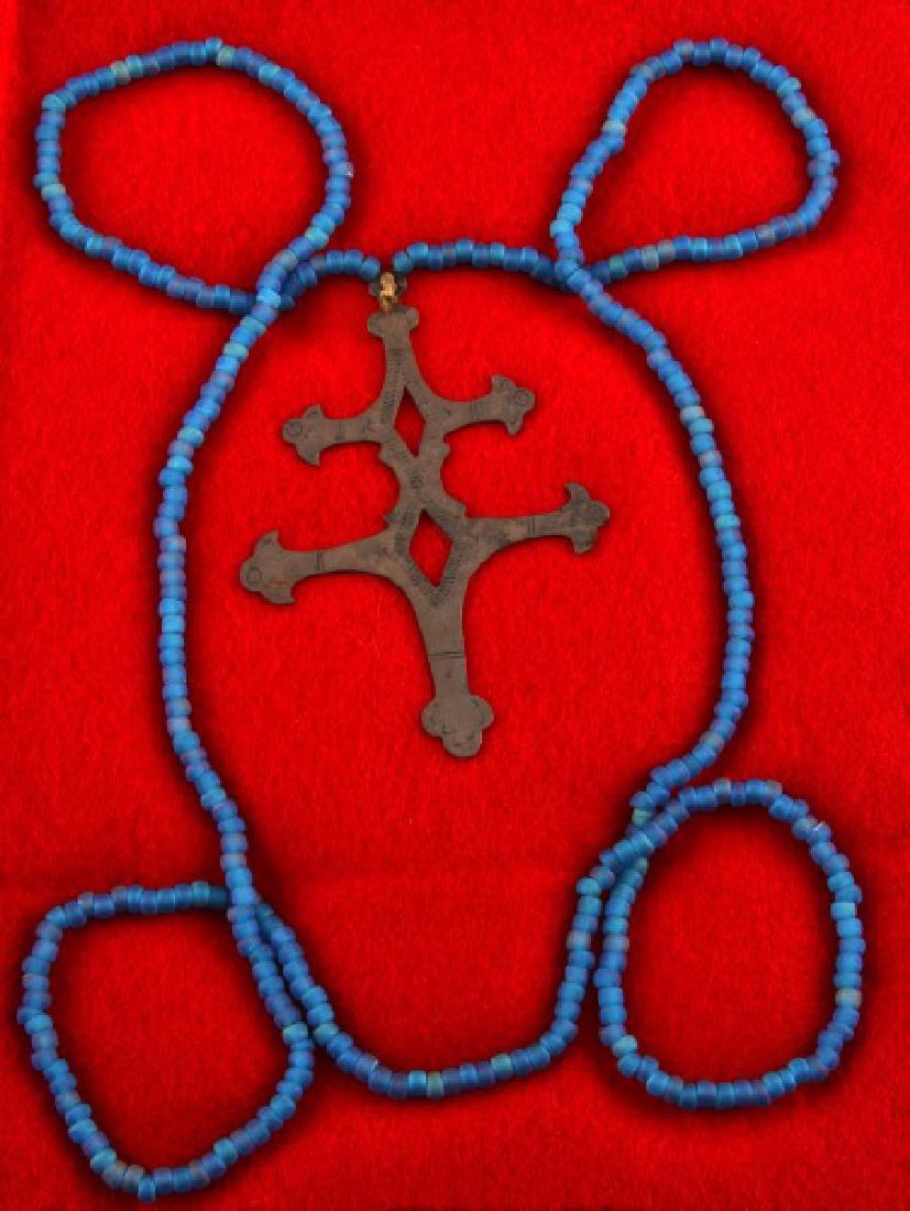 ANTIQUE NATIVE AMERICAN FUR TRADE SILVER CROSS: Silver two-barred Cross of Lorraine from the fur trade with Native Americans. No visible maker's marks or hallmarks, 3 inches in length, and has a blue Venetian bead necklace that is original to the s