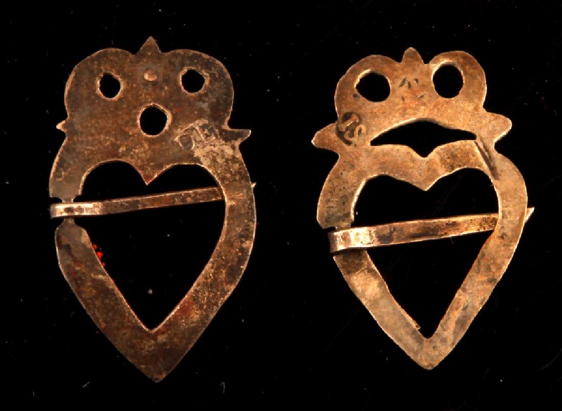 PAIR OF NATIVE AMERICAN FUR TRADE SILVER BROOCHES: Pair of Native American Silver fur trade era silver brooches both fashioned in the shape of an owl with a central heart shaped gap. Both pins bear individual manufacturer's marks, the more tarnished b