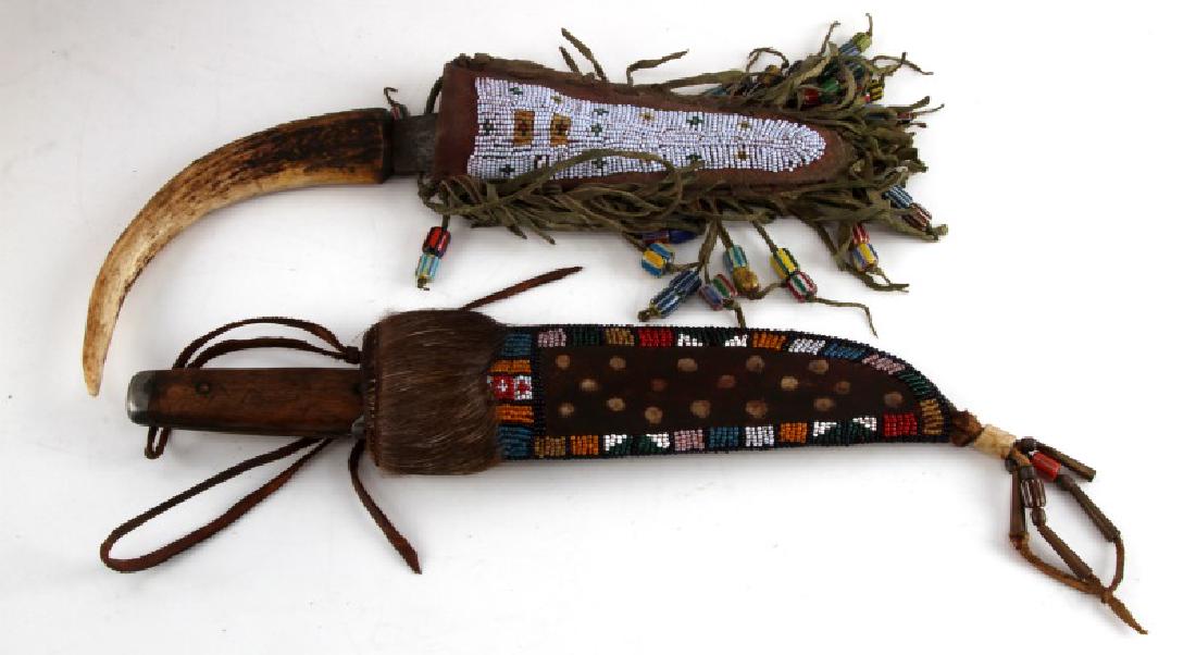 PLAINS INDIAN KNIFE AND LEATHER SCABBARD LOT OF 2: First knife 11 inches long with a 5 inch blade. In very good condition shows signs of age. Has a curved stag handle. Has a leather scabbard with beaded tassels. Second is 11 1/2 inches long with a 7 i
