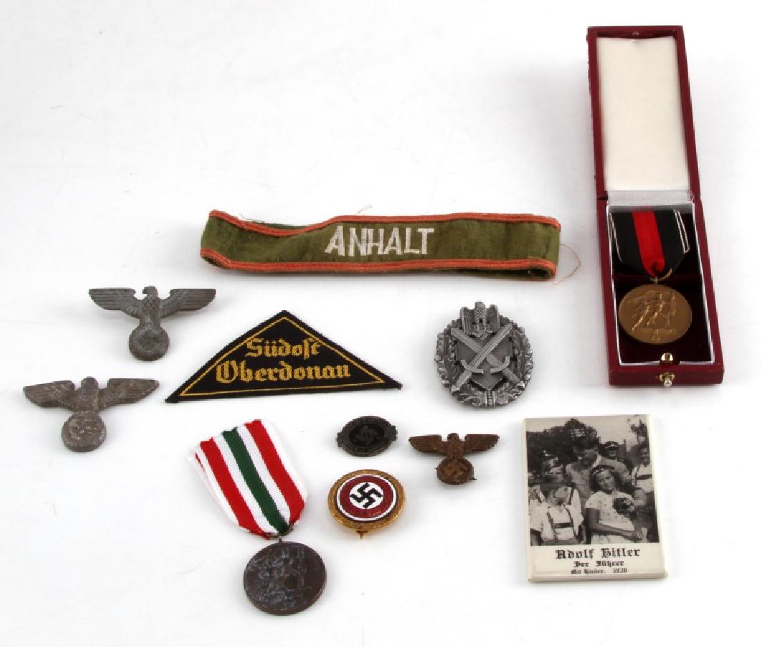 DIVERSE LOT GERMAN WWII PINS CAP EAGLES MEDALS TIN: Diverse lot of German WWII items. Includes NSDAP pin, 3 cap eagles, SS pin, medal with presentation box, patch, Hitler hand mirror, "Anhalt" cuff title, and more. G-EXC condition.