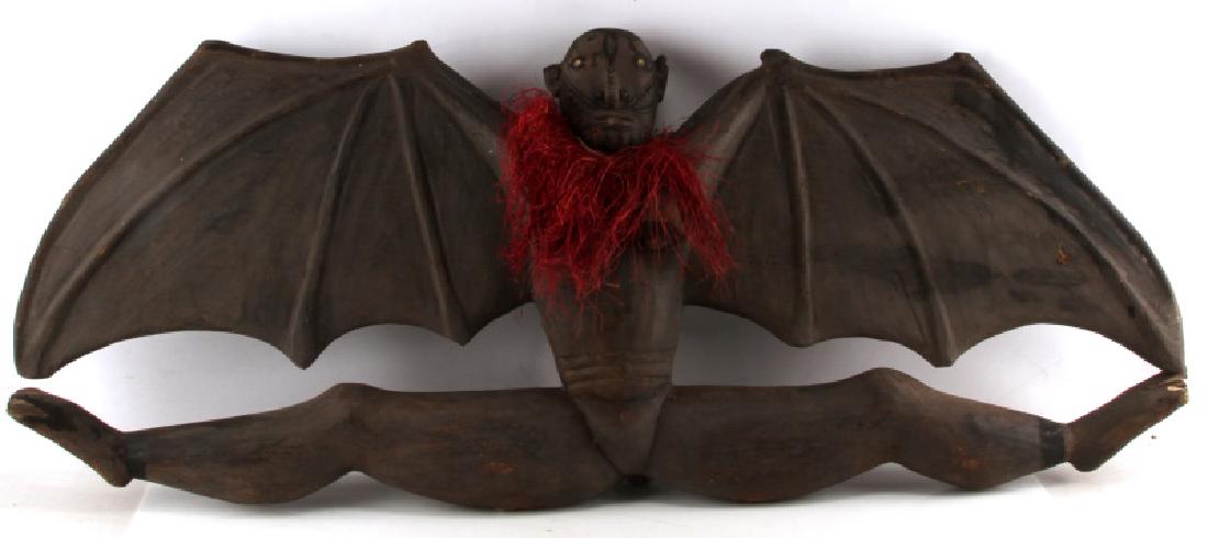 47 INCH VINTAGE NATIVE AMERICAN WOODEN BAT DEITY: Vintage or older Native American (?) bat deity statue with tribal painting on face. 47 inch wingspan. Stands approx. 19 inches tall. Some wood is chipped/damaged in a few places. Maroon scarf is made