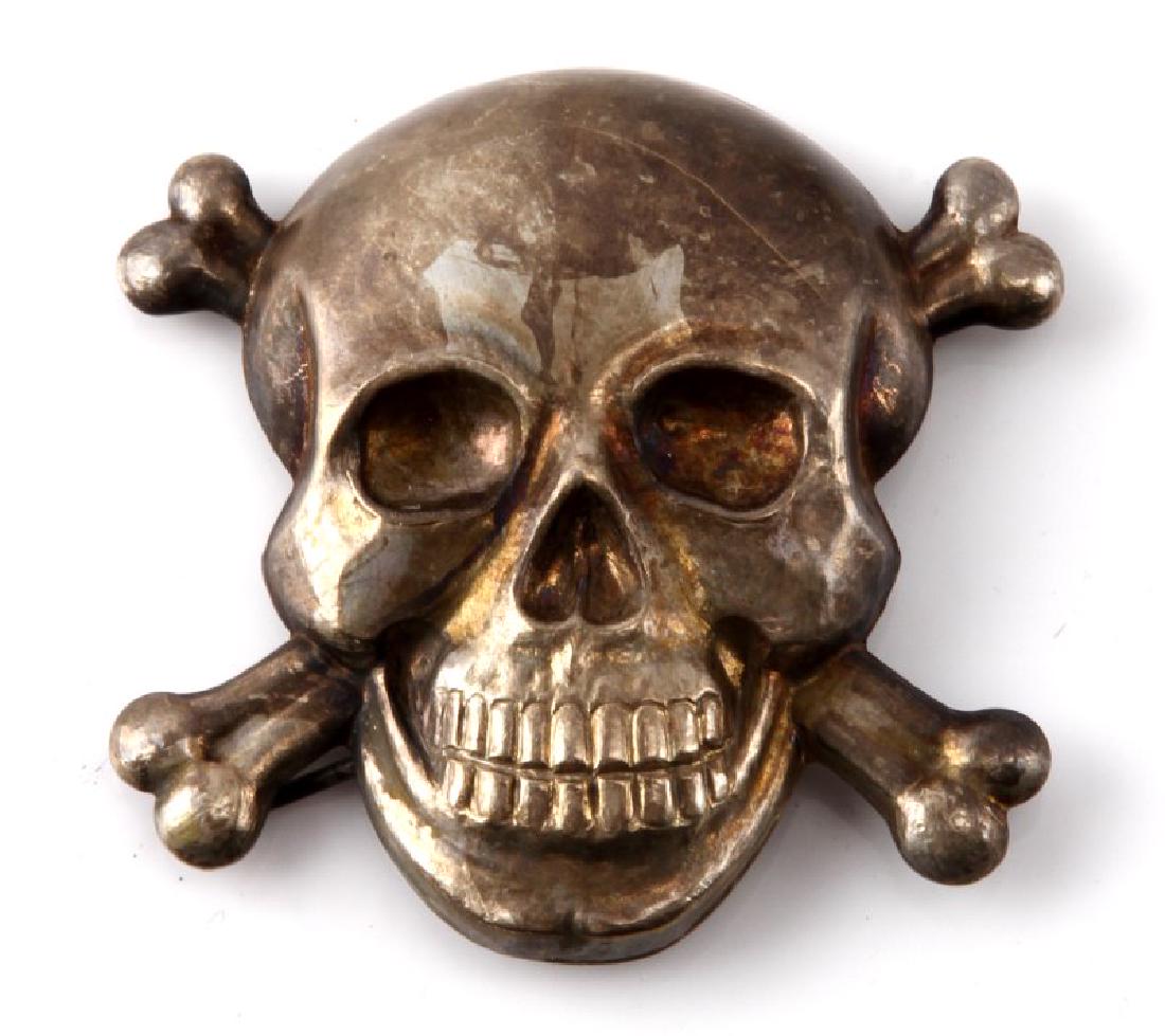 GERMAN ITALY WWII WAFFEN SS TOTENKOPF CAP INSIGNIA: German Italian WWII Waffen SS axis skull & bones (Totenkopf) cap insignia. Measures approx. 1 7/8 inches (W) by 1 7/8 inches (T). Has four (4) round prongs on reverse. Stamped nickel construction. Som