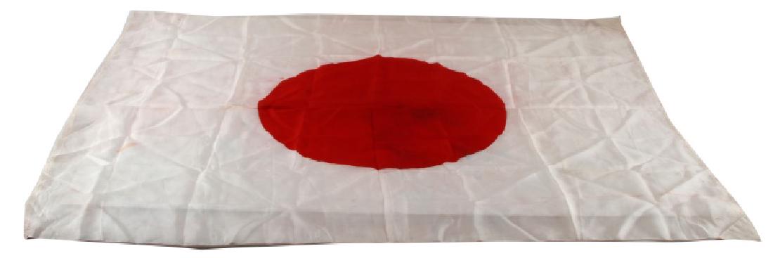 WWII JAPANESE SILK MEATBALL RISING SUN FLAG: Single-piece construction silk flag with the red rising sun of the Japanese national flag printed in red ink. Has reinforcing tabs on the corner of the hoist to reinforce the material while flown. In 
