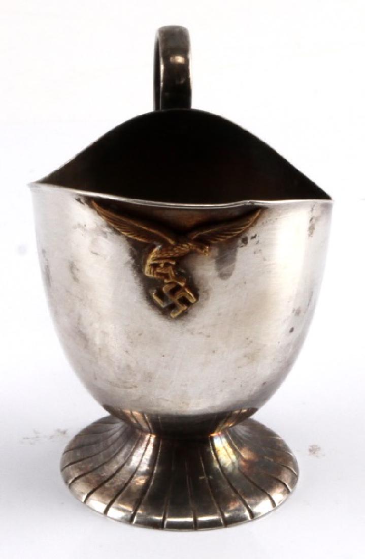 GERMAN WWII LUFTWAFFE COFFEE CREAMER PITCHER: From a Luftwaffe officer's canteen. Makers marks to underside of base. Some wear and tarnish present. Stands approx. 3 inches tall with raised Luftwaffe eagle insignia on front. This lot has a reserve