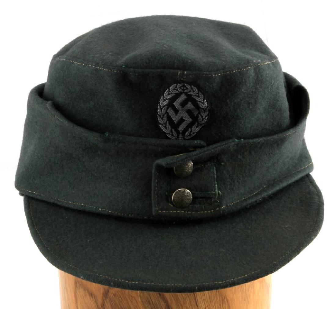 GERMAN WWII M43 SCHUTZMANNSCHAFT FIELD CAP: German/Latvian Schutzmannschaft WWII M43 field cap. Original insignia patch on face. Original pebble buttons. Eagle stamp and 58 size stamp on interior. Interior rim has light soiling from wear. Overa