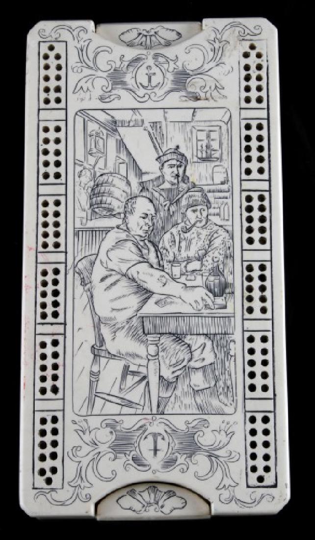ANTIQUE STYLE FAUX SCRIMSHAW GAMBLING BOARD BOX: Faux ivory gambling box with two packs of cards, a set of poker dice, and a cribbage board on top. The top and sides of the box have a nautical theme scrimshaw design, depicting a tavern scene on the 