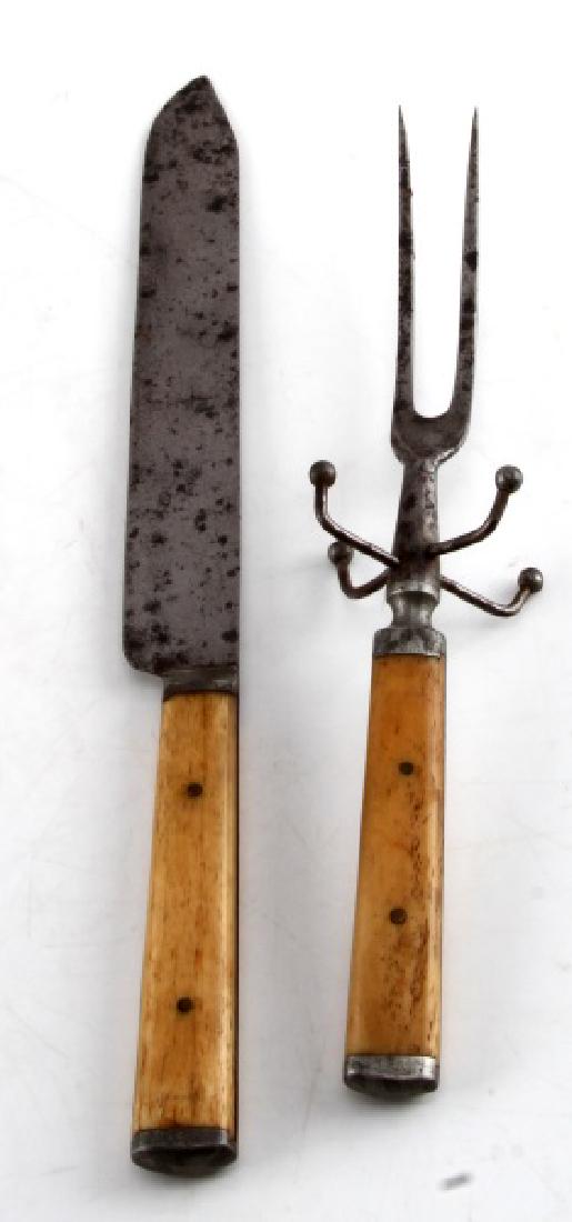 ANTIQUE CARVING SET WITH BONE HANDLES: Knife has 8 inch blade with 5 inch bone handle. Fork measures 10 1/2 inches in total. Both have notable use wear and discoloration.