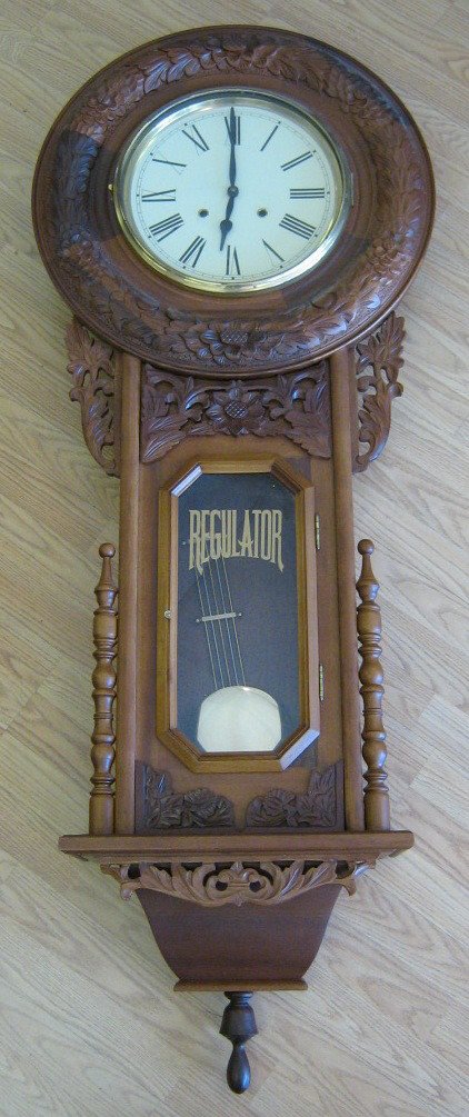LARGE WALL MOUNT BURL WOOD REGULATOR CLOCK: Burl Wood Regulator Clock, Hand Crafted Wood Ornamentation Brass pendulum, Roman numeral dial, wind mechanism in fine working order, 58" x 23"