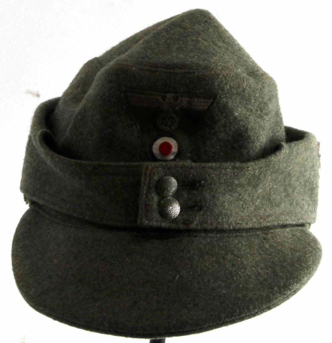 WWII GERMAN THIRD REICH M43 ARMY FIELD CAP: M43 field cap in grey-green wool. Has bevo-cloth Reichsadler with cockade, as well as a 1/2 inch tall Cross of Lorraine sewn onto the left side of the cap. In very good condition. Does not fluoresce u