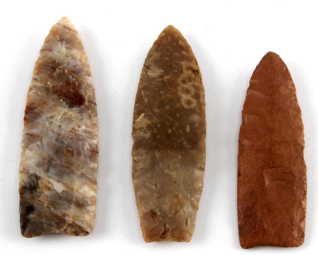 PALEO HAND CLEAVED CLOVIS ARROWHEAD LOT OF 3: Grouping of 3 Neolithic hand cleaved Clovis arrow heads. All of which appear to be made of a metamorphic stone. Each shows a partial semi circle for fastening. They measure 3 3/8", 3 3/8", and 3". All