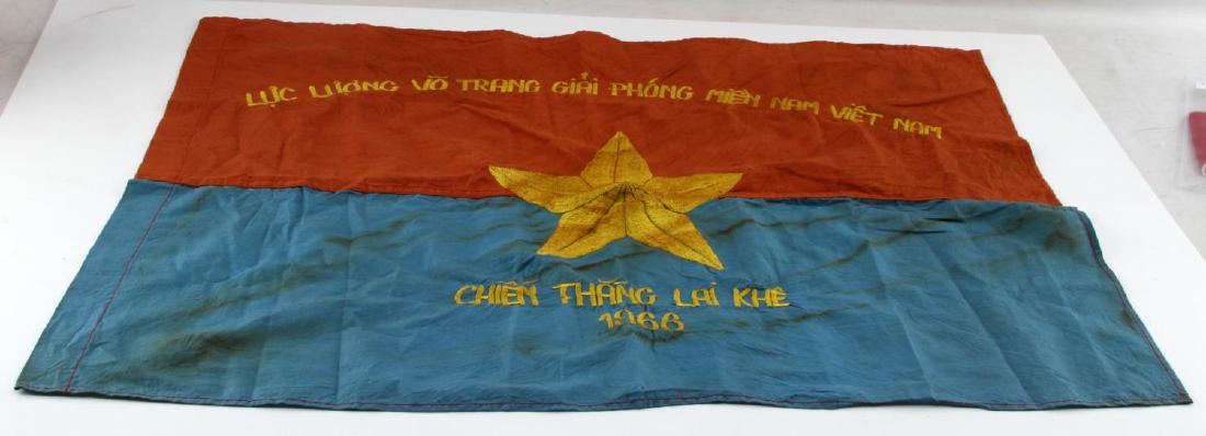 VIETNAM ERA VIET CONG VG COMBAT BATTLE FLAG: Measures 28 1/4" wide by 20 3/4" tall. Machine embroidered yellow star in center. Writing above and below star reads 'Luc Luong Vo Trang Giai Phong Mien Nam Viet Nam Chien Thank Lai Kue'. Dated 1966. 