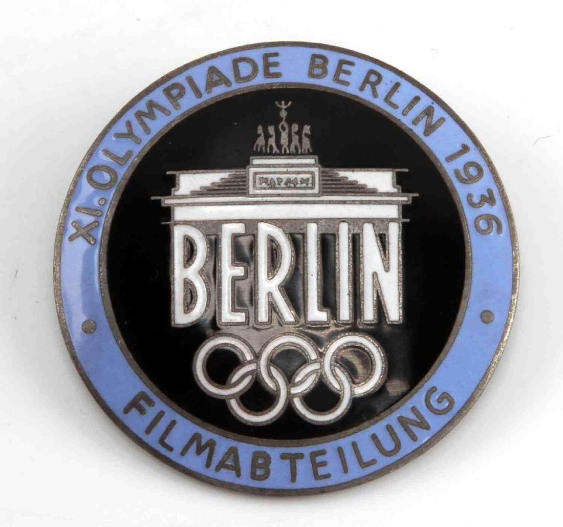 GERMAN WWII 1936 BERLIN OLYMPICS FILMMAKER BADGE: 1 1/2 inch diameter. Reverse maker marked "Rob Neff Berlin W 57". This horizontal pin back. One-piece nickel and light blue enamel construction. Unauthenticated. Sold "as is".