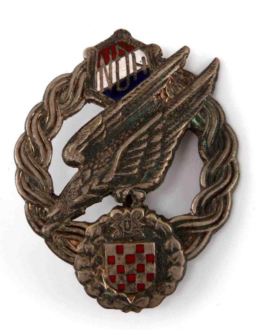 GERMAN WWII LUFTWAFFE CROATION PARATROOPER BADGE: Luftwaffe Croation Paratrooper Fallschirmjager Jump Badge. Measures 1 5/8 (W) x 2 1/16 (T) inches. Wide vertical pin back. One-piece nickel construction with enamel highlights. Some wear is present. U