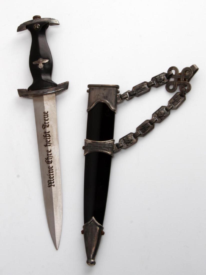 GERMAN WWII WAFFEN SS MINIATURE OFFICERS DAGGER: Inlcudes dagger, scabbard, and chain. Measures 7 1/4 inches. Etched steel blade reads "Meine Ehre heist Treue". Blade measures 5.8 inches wide by 4 1/4 inches long. Has black painted wooden handle. Al