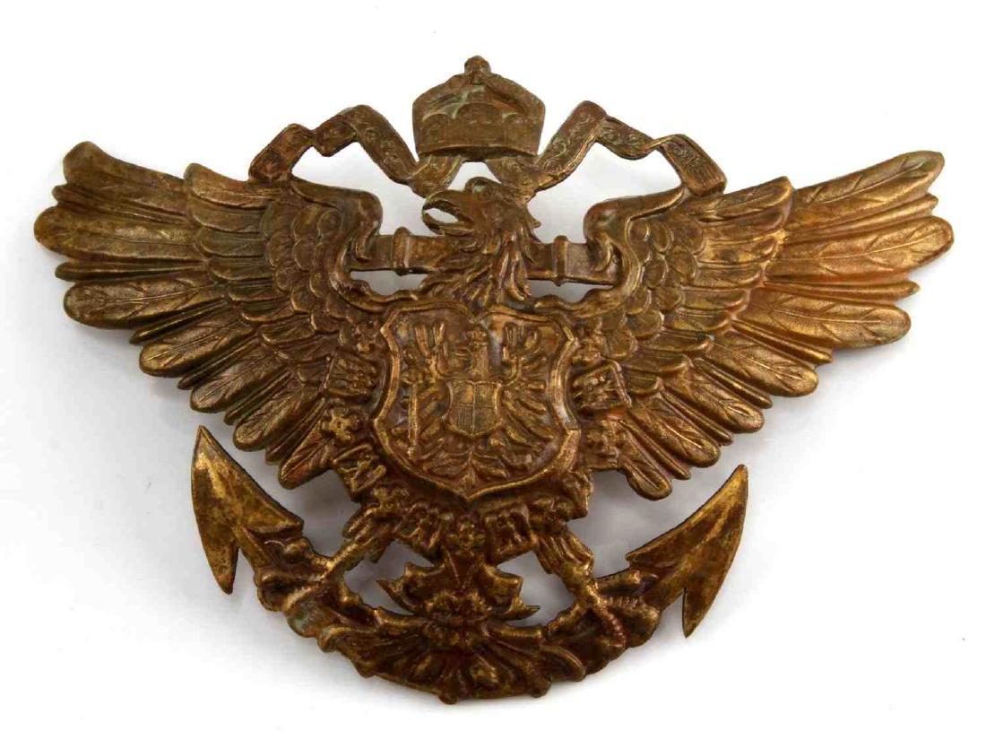 GERMAN WWI NAVAL KREIGSMARINE SPIKE HELMET PLATE: Imperial German Naval Kreigsmarine spike helmet front plate. Approximately 5 3/16 x 3 1/2 inches. Reverse has two screw mount posts with nuts. Stamped brass construction. Scarce. Some wear/tarnish is 