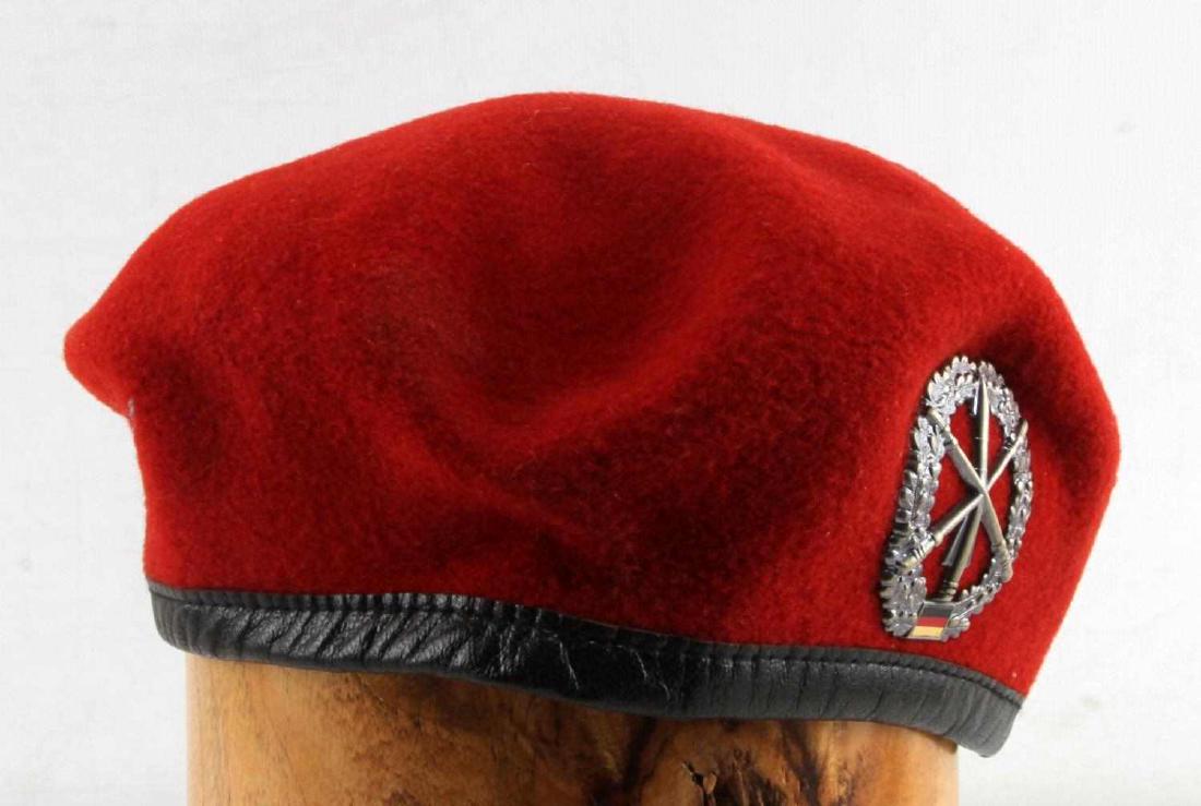 COLD WAR ERA GERMAN RED BARET CAP WITH BADGE: Post WWII German red beret cap. Black leather liner. Sweat Shield marked '56' for size. Badge on exterior shows minimal tarnishing. VG condition. Unauthenticated, sold as is.