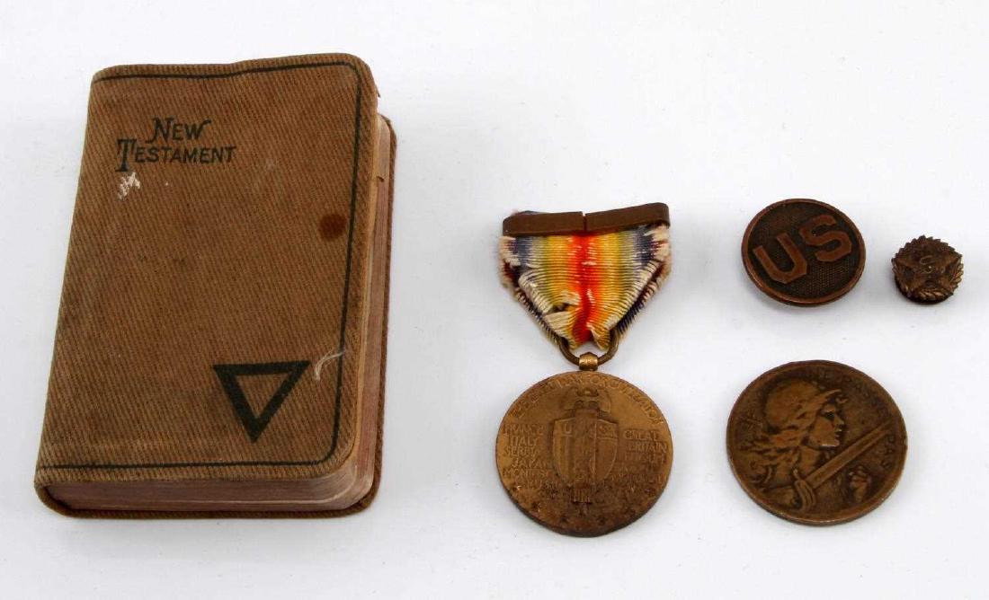 WWI US SOLDIER PERSONAL ITEM LOT OF FIVE: Lot contains five personal items of a US WWI soldier. Includes a US collar badge, a 1918 marked New Testament, a WWI Victory Medal, a small US badge, and a coin version of the French Verdun medal.