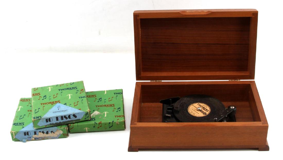 THORENS SWISS MUSIC BOX DISC PLAYER: Solid wood box, metal disc music player with 31 disc's in total, 10 of which are Christmas tunes, in their original boxes and in good working condition.