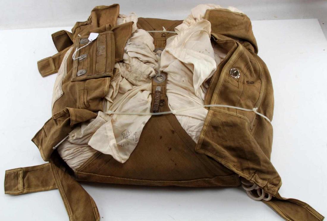 WWII GERMAN LUFTWAFFE PILOT SEAT TYPE PARACHUTE: Seat-type parachute used by a German Luftwaffe pilot. Parachute exhibits some wear from what can be inspected in its current form, as it has not been unfolded or properly repacked. Canvas bag also dis