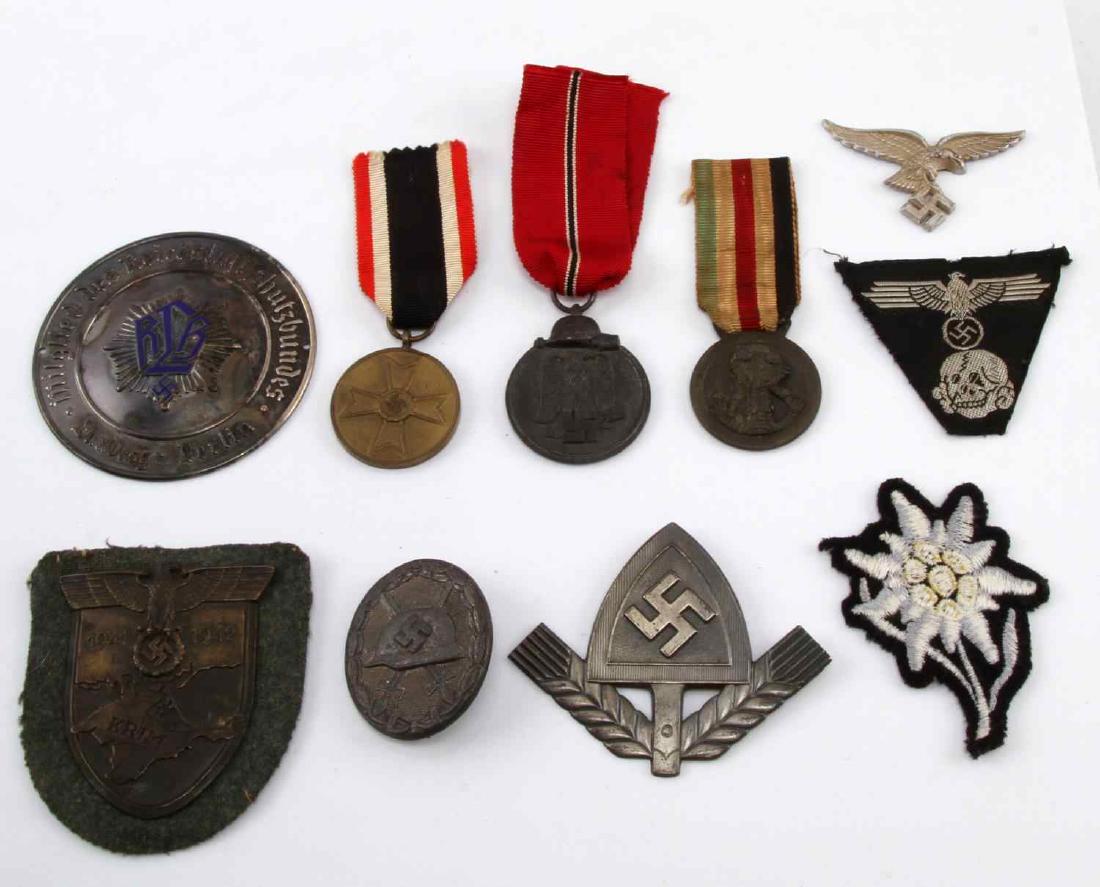 LOT OF 10 GERMAN WWII BADGES MEDALS PATCHES MORE: Lot of 10 German WWII items. Includes Waffen SS patch, RLB plate, KRIM sleeve shield, Luftwaffe cap eagle, War Merit medal, Wound badge in silver (107 maker stamped), Edelweiss patch, 2 medals, and 1 