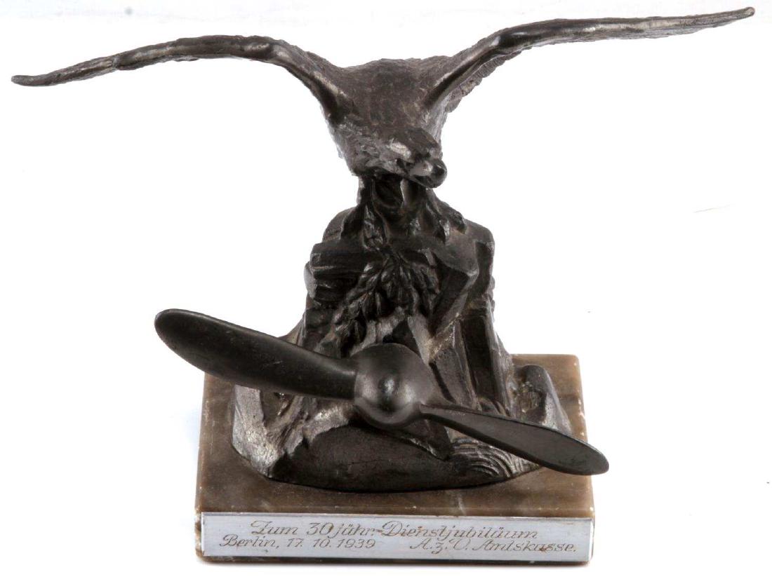POST WWII LUFTWAFFE PILOT SERVICE DESK ORNAMENT: Desk ornament likely meant to serve as a commemorative to a Luftwaffe veteran from WWII. Depicts an eagle with outspread wings and a propellor on plinth. The base of the ornament has 'Zum 30 Jähr Die
