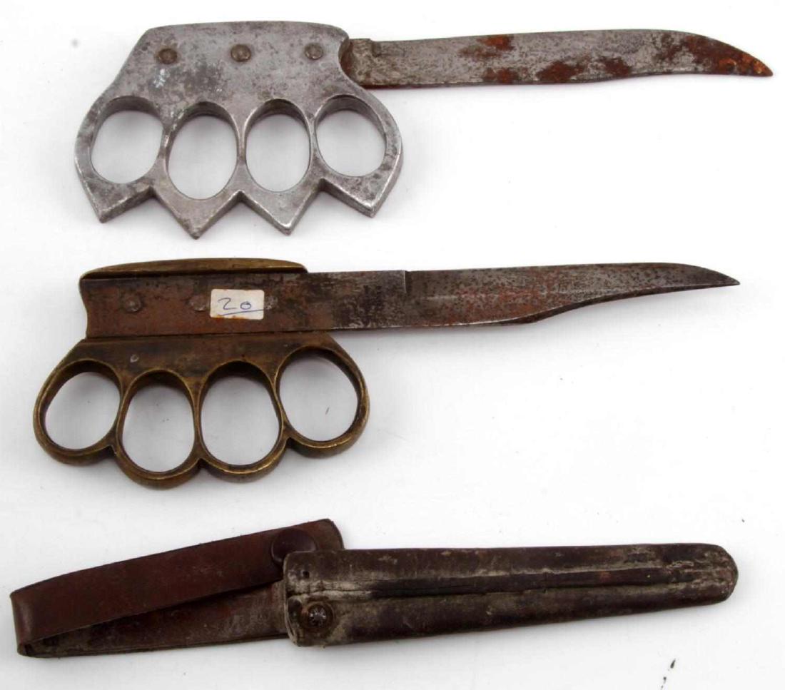 2 RARE WWI SHEATHED KNUCKLE DUSTER TRENCH KNIFES: 2 rare WWI "knuckle duster" trench knives, one in steel and the other brass. 5 1/4" bladed brass variant shows maker stamp on blade and comes included with leather sheath. Steel variant features a 5 1