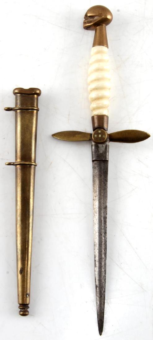 SMALL INTERWAR BONE HANDLE PROPELLER SKULL DAGGER: Small dagger from the interwar era with a bone handle, crossguard formed like a propeller, and the pommel shaped like a skull. Measures just short of 8 1/2 inches long in the scabbard. The crossguard