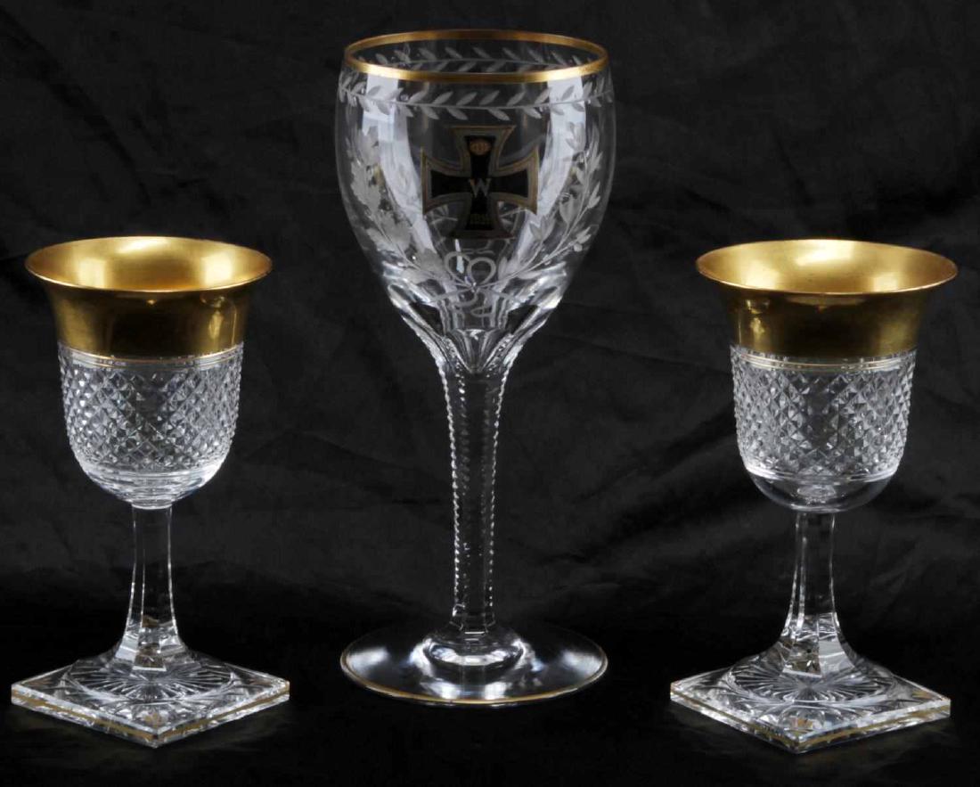 2 CRYSTAL GLASSES WITH 1 GOBLET WITH IRON CROSS: 3 glasses total. Includes: 2 gold trimmed 5.5 inch wine glasses with square base and one etched goblet with iron cross painted to front center, measures 8 inches tall. One of the smaller glasses has c