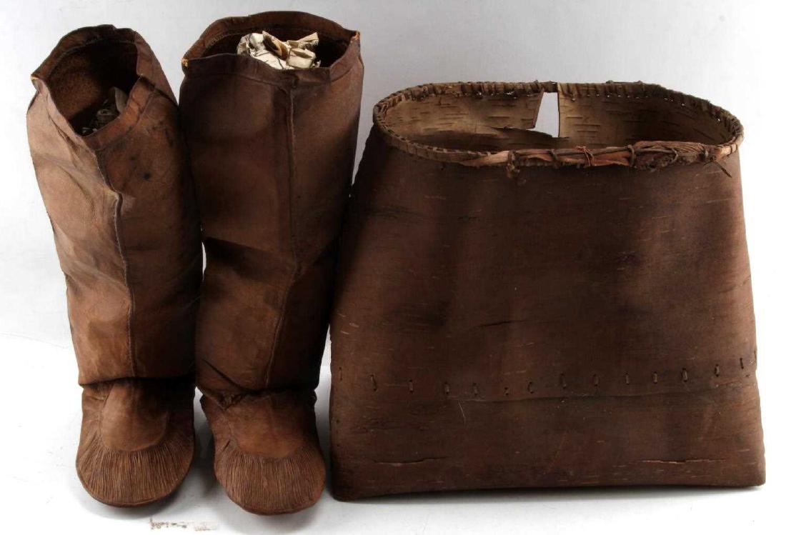 FUR TRADE MOCCASINS & CHIPPEWA BIRCH BASKET 1800S: Lot contains 2 leather moccasins measuring 11" from heel to toe and standing 16" tall, appears to be early machine sewn. Lot also contains 1 Chippewa birch "burden basket" measuring 18" wide and 14" t