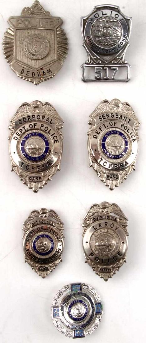 UNITED STATES POLICE DEPARTMENT OBSOLETE BADGE LOT: Seven obsolete police badges from different cities across the US. Includes three Topeka, Kansas badges of the ranks of Corporal, Sergeant, and Detective, as well as a Dedham, Massachusetts PD badge, L